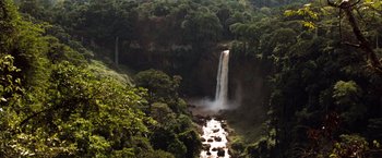 Movie still from “Greystoke: The Legend of Tarzan, Lord of the Apes” (1984), directed by Hugh Hudson – A view of a waterfall in the middle of a forest; Extreme Wide shot, High angle