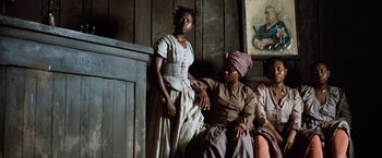 Movie still from “Greystoke: The Legend of Tarzan, Lord of the Apes” (1984), directed by Hugh Hudson – Two women sitting on a couch in a room; Medium shot, Low angle