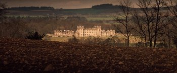 Movie still from “Greystoke: The Legend of Tarzan, Lord of the Apes” (1984), directed by Hugh Hudson – A large building in the middle of a field; Extreme Wide shot, High angle