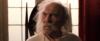 Movie still from “Greystoke: The Legend of Tarzan, Lord of the Apes” (1984), directed by Hugh Hudson – An old man with a white beard is looking at the camera; Close Up shot, Low angle