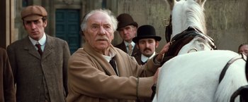 Movie still from “Greystoke: The Legend of Tarzan, Lord of the Apes” (1984), directed by Hugh Hudson – An old man wearing a brown coat and a hat; Close Up shot, Low angle