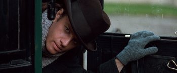 Movie still from “Greystoke: The Legend of Tarzan, Lord of the Apes” (1984), directed by Hugh Hudson – A young man wearing a hat in a car; Close Up shot, Low angle