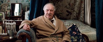 Movie still from “Greystoke: The Legend of Tarzan, Lord of the Apes” (1984), directed by Hugh Hudson – An older man sitting on a couch wearing a robe; Medium shot, High angle