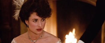 Movie still from “Greystoke: The Legend of Tarzan, Lord of the Apes” (1984), directed by Hugh Hudson – A person wearing a necklace near a fire; Close Up shot, Over the shoulder angle