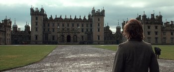 Movie still from “Greystoke: The Legend of Tarzan, Lord of the Apes” (1984), directed by Hugh Hudson – A large building with a lot of steeples on top of it; Extreme Wide shot, Over the shoulder angle