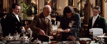 Movie still from “Greystoke: The Legend of Tarzan, Lord of the Apes” (1984), directed by Hugh Hudson – A man and a woman serving food at a dinner table; Medium shot, Low angle