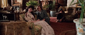 Movie still from “Greystoke: The Legend of Tarzan, Lord of the Apes” (1984), directed by Hugh Hudson – A man and a woman sitting on a couch in a living room; Wide shot, Over the shoulder angle