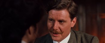 Movie still from “Greystoke: The Legend of Tarzan, Lord of the Apes” (1984), directed by Hugh Hudson – A person wearing a suit and tie; Close Up shot, Over the shoulder angle