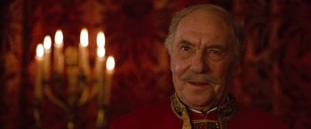 Movie still from “Greystoke: The Legend of Tarzan, Lord of the Apes” (1984), directed by Hugh Hudson – An older man in a red and gold jacket; Close Up shot, Over the shoulder angle