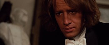 Movie still from “Greystoke: The Legend of Tarzan, Lord of the Apes” (1984), directed by Hugh Hudson – A person wearing a suit and bow tie; Close Up shot, Over the shoulder angle