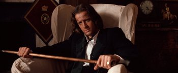 Movie still from “Greystoke: The Legend of Tarzan, Lord of the Apes” (1984), directed by Hugh Hudson – A man sitting in a chair holding a wooden stick; Close Up shot, Low angle