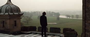 Movie still from “Greystoke: The Legend of Tarzan, Lord of the Apes” (1984), directed by Hugh Hudson – A man standing on a balcony looking out over a field; Wide shot, Low angle