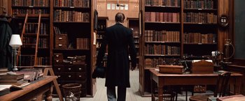 Movie still from “Greystoke: The Legend of Tarzan, Lord of the Apes” (1984), directed by Hugh Hudson – A man walking through a room full of bookshelves; Wide shot, Low angle