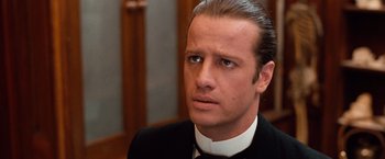 Movie still from “Greystoke: The Legend of Tarzan, Lord of the Apes” (1984), directed by Hugh Hudson – A person wearing a suit and tie; Close Up shot, Over the shoulder angle