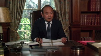 Movie still from “Gross Anatomy” (1989), directed by Thom Eberhardt – A man sitting at a desk with papers in front of him; Medium shot, Low angle
