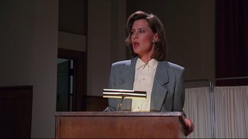Movie still from “Gross Anatomy” (1989), directed by Thom Eberhardt – A woman is standing at a podium speaking to a crowd; Medium shot, Low angle