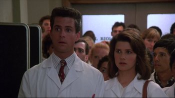 Movie still from “Gross Anatomy” (1989), directed by Thom Eberhardt – A man and a woman in white lab coats in front of a group of people; Medium shot, Low angle