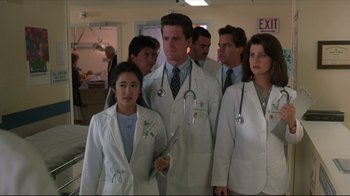 Movie still from “Gross Anatomy” (1989), directed by Thom Eberhardt – A group of doctors standing next to each other in a room; Medium shot, Low angle
