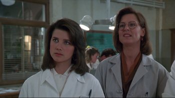 Movie still from “Gross Anatomy” (1989), directed by Thom Eberhardt – Two women in lab coats standing next to each other in a classroom; Close Up shot, Low angle