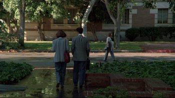 Movie still from “Gross Anatomy” (1989), directed by Thom Eberhardt – Two people are walking down the sidewalk in the rain; Wide shot, High angle