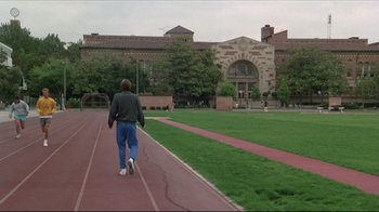 Movie still from “Gross Anatomy” (1989), directed by Thom Eberhardt – A man walking on a track in front of a building; Extreme Wide shot, High angle