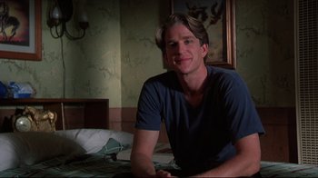 Movie still from “Gross Anatomy” (1989), directed by Thom Eberhardt – A man sitting on top of a bed in a room; Medium shot, Low angle