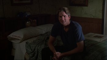 Movie still from “Gross Anatomy” (1989), directed by Thom Eberhardt – A man sitting on a bed in a dark room; Medium shot, Over the shoulder angle