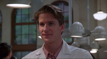 Movie still from “Gross Anatomy” (1989), directed by Thom Eberhardt – A man wearing a lab coat in front of some lights; Close Up shot, Low angle