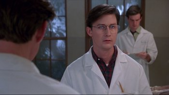 Movie still from “Gross Anatomy” (1989), directed by Thom Eberhardt – A man in a white lab coat looking at himself in the mirror; Close Up shot, Over the shoulder angle