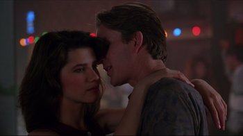 Movie still from “Gross Anatomy” (1989), directed by Thom Eberhardt – A man and a woman embracing each other in a dark room; Close Up shot, Low angle