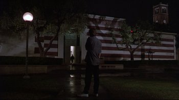 Movie still from “Gross Anatomy” (1989), directed by Thom Eberhardt – A man standing in front of a building at night; Extreme Wide shot, Low angle