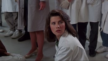 Movie still from “Gross Anatomy” (1989), directed by Thom Eberhardt – A woman in a white lab coat is sitting in front of a group of people; Close Up shot, Low angle