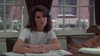 Movie still from “Gross Anatomy” (1989), directed by Thom Eberhardt – A woman sitting at a table with papers in front of a window; Medium shot, Over the shoulder angle