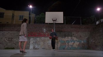 Movie still from “Gross Anatomy” (1989), directed by Thom Eberhardt – A man and a woman playing basketball on a basketball court; Wide shot, Low angle