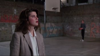 Movie still from “Gross Anatomy” (1989), directed by Thom Eberhardt – A woman in a jacket and tie standing next to a basketball hoop; Medium shot, Low angle