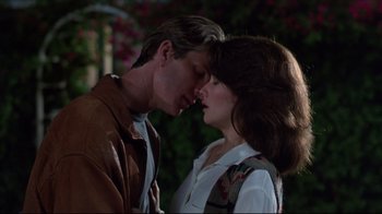 Movie still from “Gross Anatomy” (1989), directed by Thom Eberhardt – A man and a woman standing next to each other in front of a bush; Close Up shot, Low angle