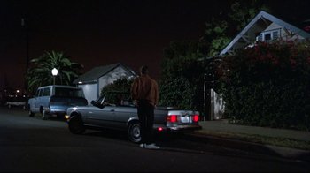 Movie still from “Gross Anatomy” (1989), directed by Thom Eberhardt – A man standing next to a car on the side of the road; Wide shot, Low angle