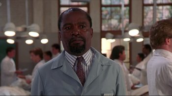 Movie still from “Gross Anatomy” (1989), directed by Thom Eberhardt – A man in a white lab coat and a tie; Close Up shot, Low angle