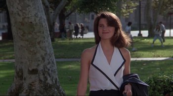 Movie still from “Gross Anatomy” (1989), directed by Thom Eberhardt – A woman in a white shirt and black skirt walking in a park; Medium shot, Low angle