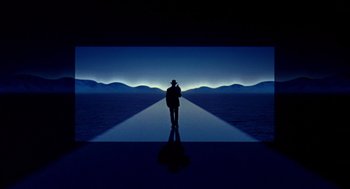 Movie still from “Grosse Pointe Blank” (1997), directed by George Armitage – A man standing in front of an image at night; Extreme Wide shot, High angle