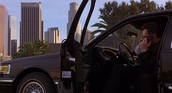 Movie still from “Grosse Pointe Blank” (1997), directed by George Armitage – A black car is parked on the side of the road; Wide shot, Low angle