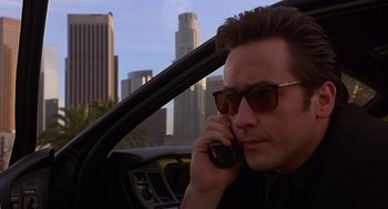 Movie still from “Grosse Pointe Blank” (1997), directed by George Armitage – A man talking on a cell phone while sitting in the drivers seat of a car; Close Up shot, Low angle