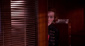 Movie still from “Grosse Pointe Blank” (1997), directed by George Armitage – A young woman looking out of a window; Medium shot, Over the shoulder angle