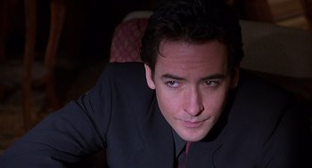 Movie still from “Grosse Pointe Blank” (1997), directed by George Armitage – A person wearing a suit and tie; Close Up shot, Low angle