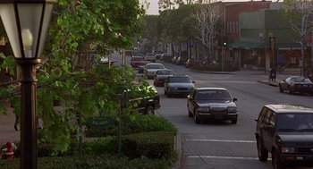 Movie still from “Grosse Pointe Blank” (1997), directed by George Armitage – Cars are driving down a street lined with trees; Extreme Wide shot, High angle