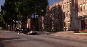 Movie still from “Grosse Pointe Blank” (1997), directed by George Armitage – A car driving down a street next to tall buildings; Extreme Wide shot, High angle