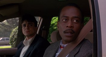 Movie still from “Grosse Pointe Blank” (1997), directed by George Armitage – Two men sitting in the back seat of a car; Close Up shot, Over the shoulder angle