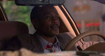 Movie still from “Grosse Pointe Blank” (1997), directed by George Armitage – A man sitting in the driver's seat of a car; Close Up shot, Low angle