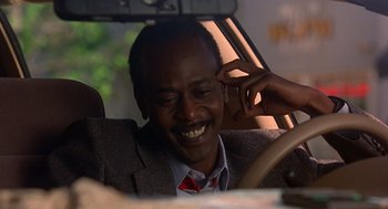 Movie still from “Grosse Pointe Blank” (1997), directed by George Armitage – A man sitting in the driver's seat of a car; Close Up shot, Low angle