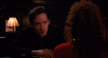 Movie still from “Grosse Pointe Blank” (1997), directed by George Armitage – A man and a woman are sitting at a table; Close Up shot, Over the shoulder angle